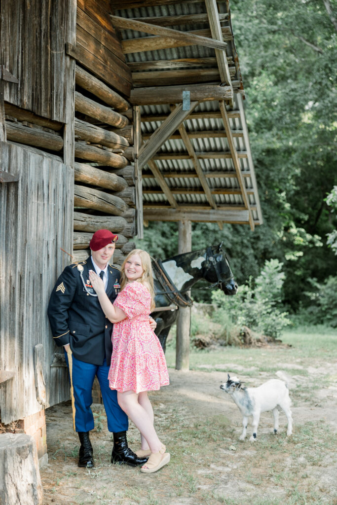 Couple posing with a baby goat that followed them during their engagement session at Gillis Hill Farm.