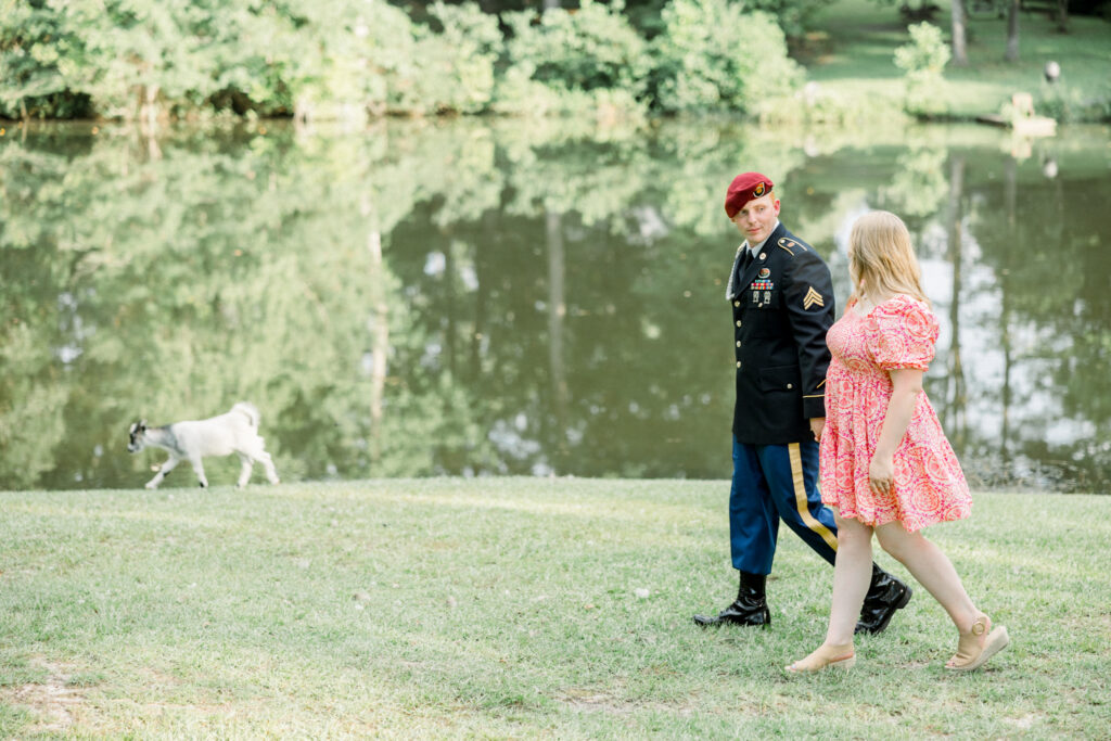 Couple posing with a baby goat that followed them during their engagement session at Gillis Hill Farm.
