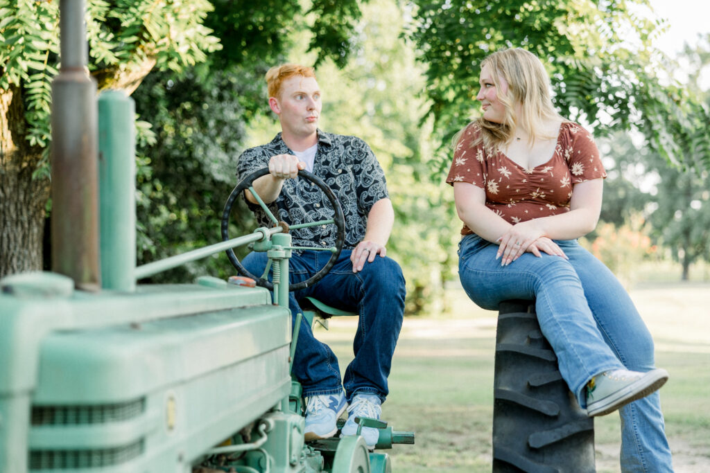 Couple posing on a tractor at the chic Gillis Hill Farm during their engagement session