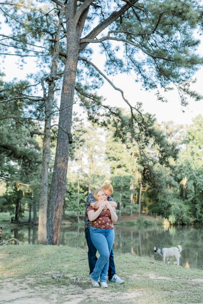 Couple posing with a baby goat that followed them during their engagement session at Gillis Hill Farm.