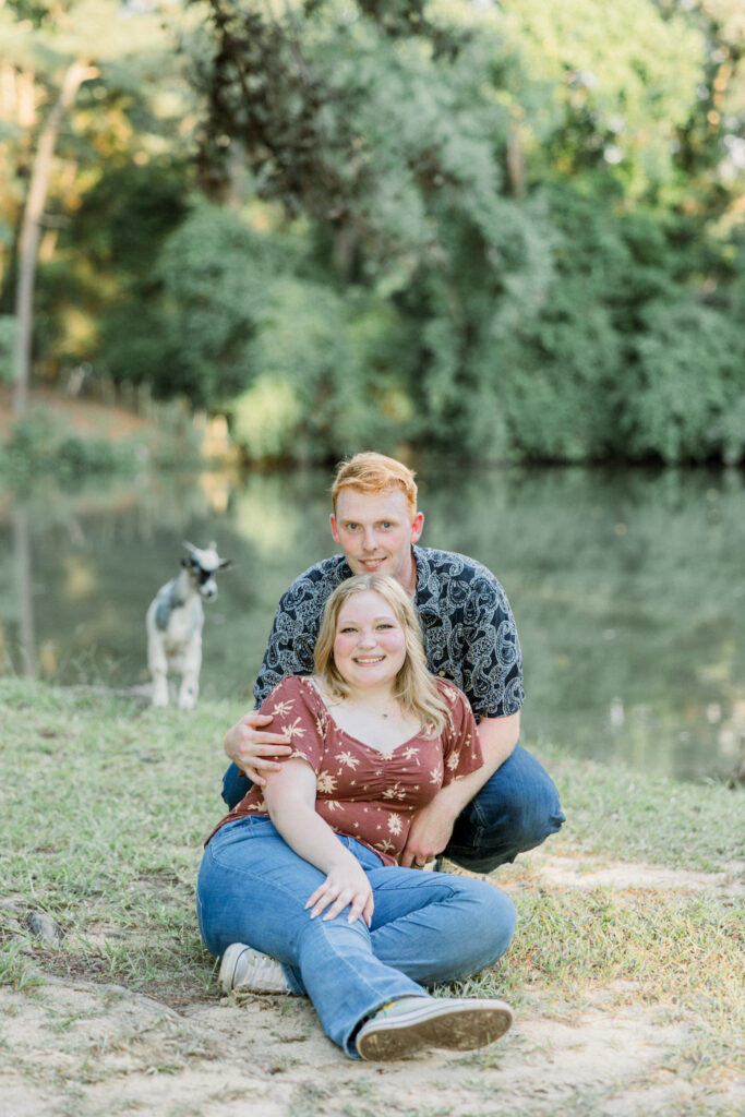 Couple posing with a baby goat that followed them during their engagement session at Gillis Hill Farm.