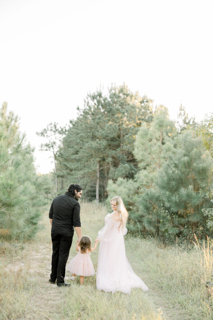 Family walking hand-in-hand through a field during sunset