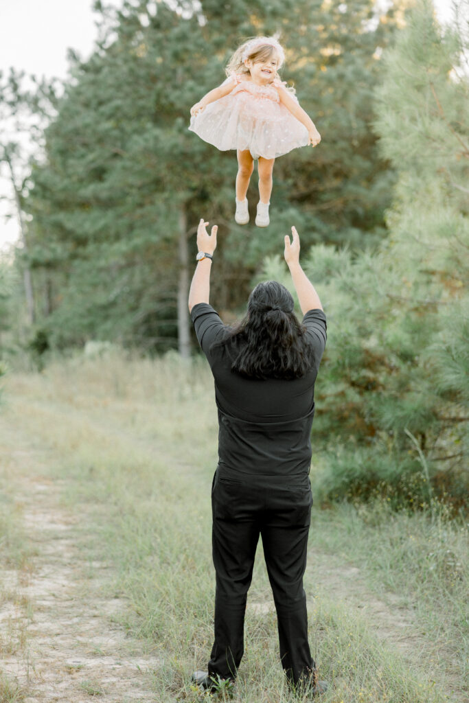 Father lifting toddler in the air during sunset photos in open field