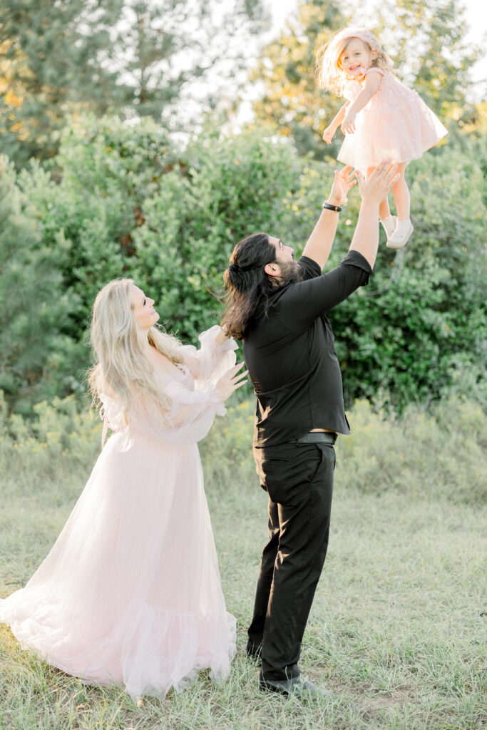 Father lifting toddler in the air during sunset photos in open field