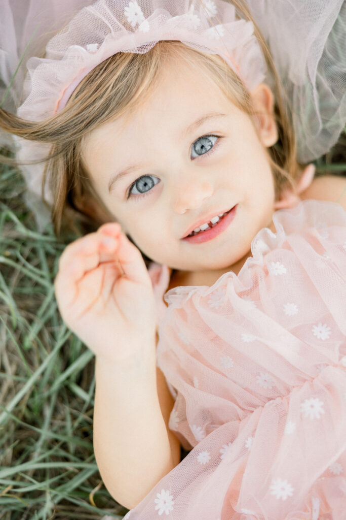 Toddler with bright blue eyes and pink dress during family photos